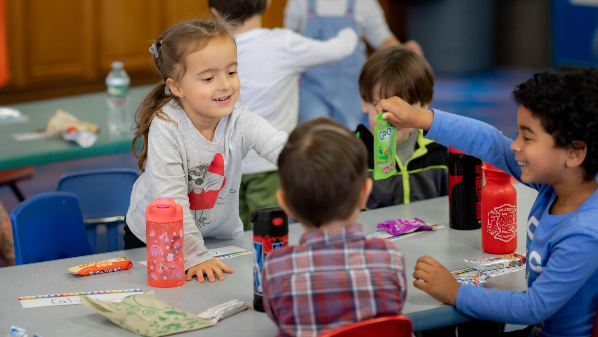 Children sharing snacks at a classroom table.