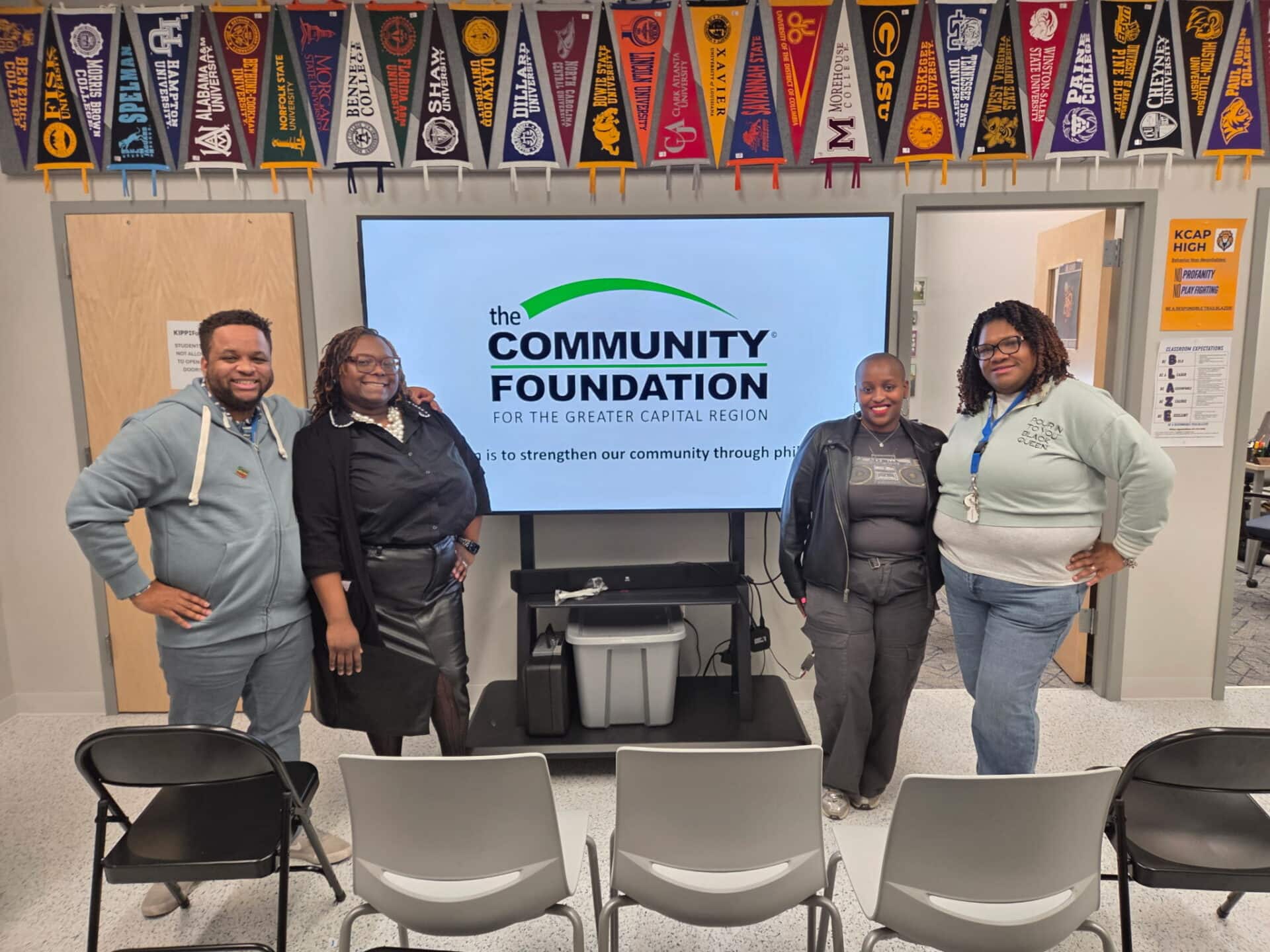 Four people posing before Community Foundation for Greater Capital Region screen