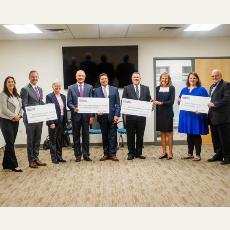 Group holding oversized Community Foundation grant checks indoors