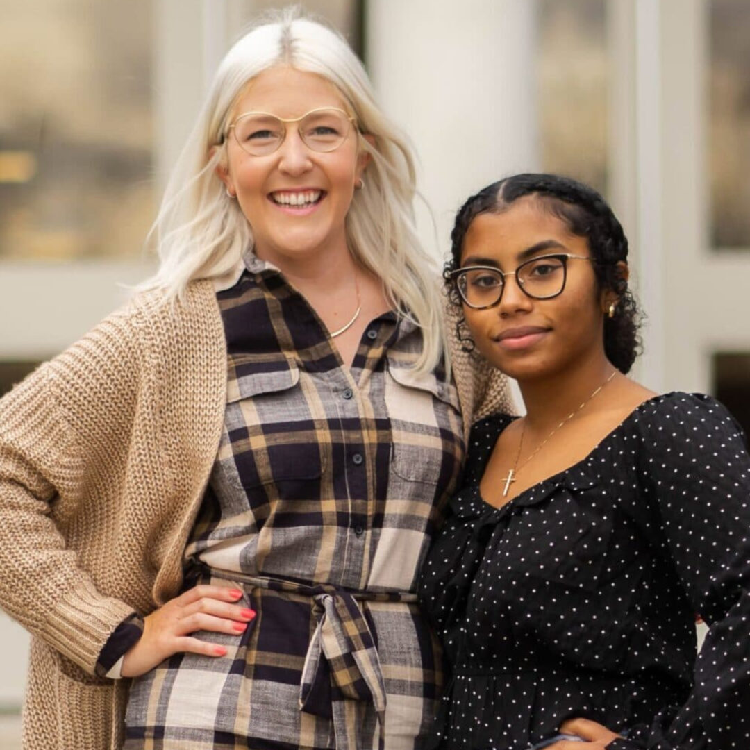 Two women smiling together indoors in casual attire