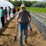 Man with tools walking in greenhouse garden