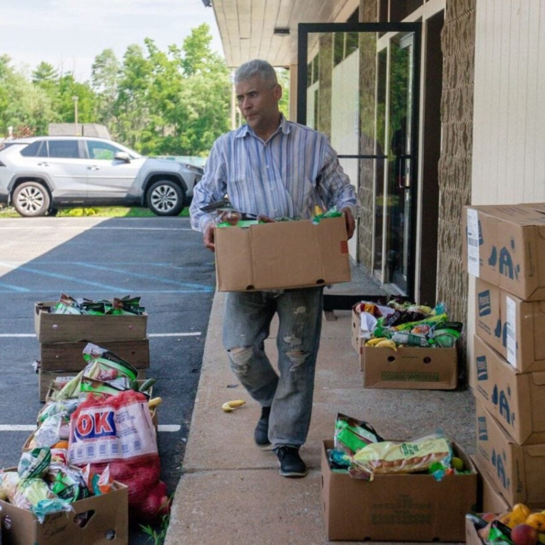 Man carrying cardboard box at outdoor food distribution site