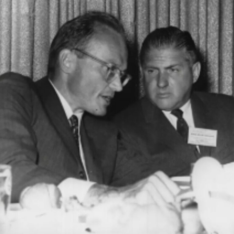 Two men in suits having a discussion at a formal event