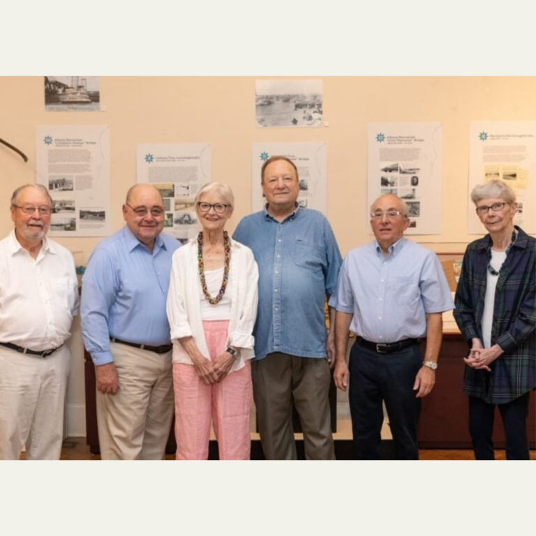 Six seniors posing together at a historical exhibit