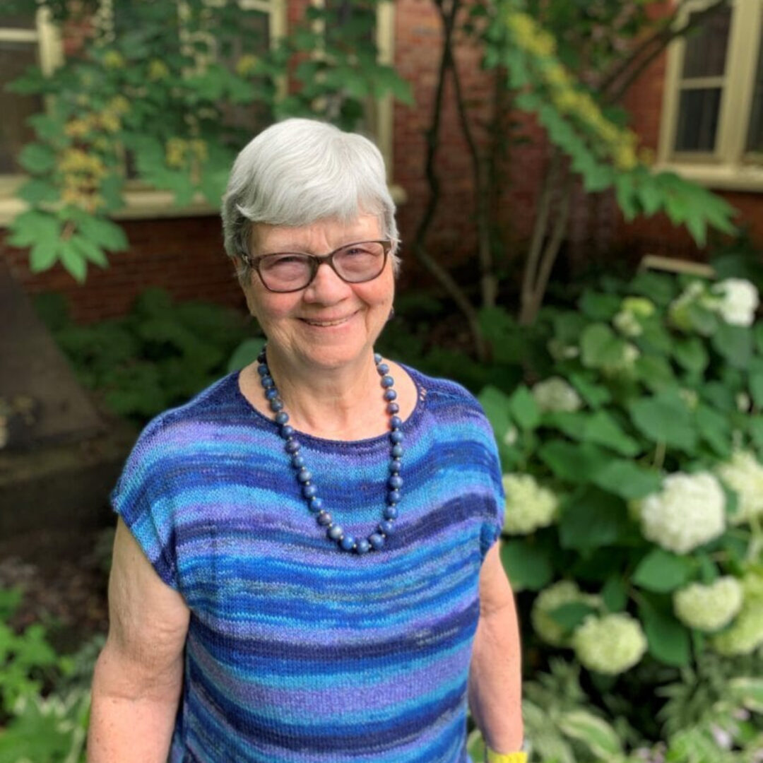 Smiling elderly woman in blue top standing in garden
