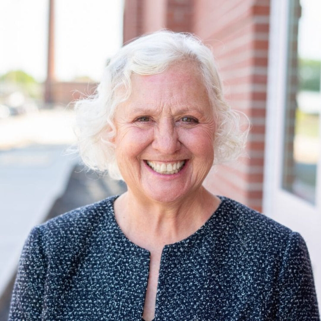 Smiling elderly woman with white curly hair outdoors