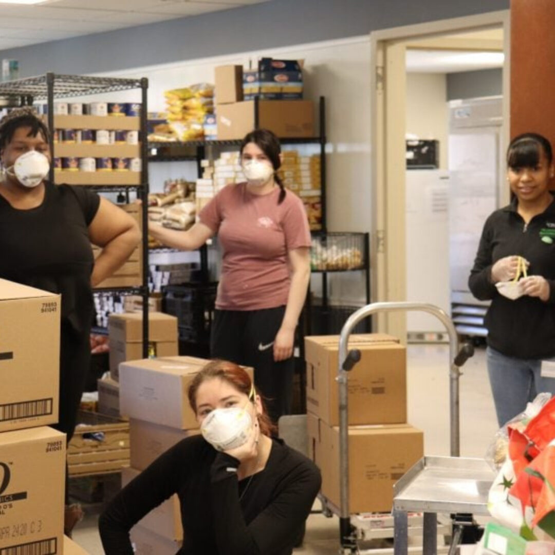 Four masked volunteers working at a food pantry