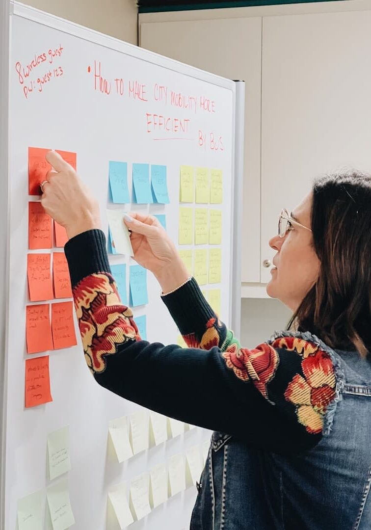 Woman organizing colorful sticky notes on a whiteboard