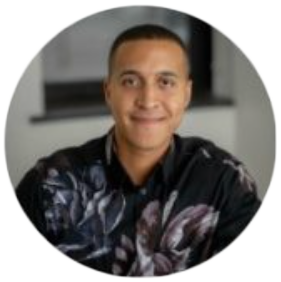 Smiling person wearing floral shirt indoors.