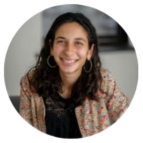 Smiling person with curly hair and hoop earrings.