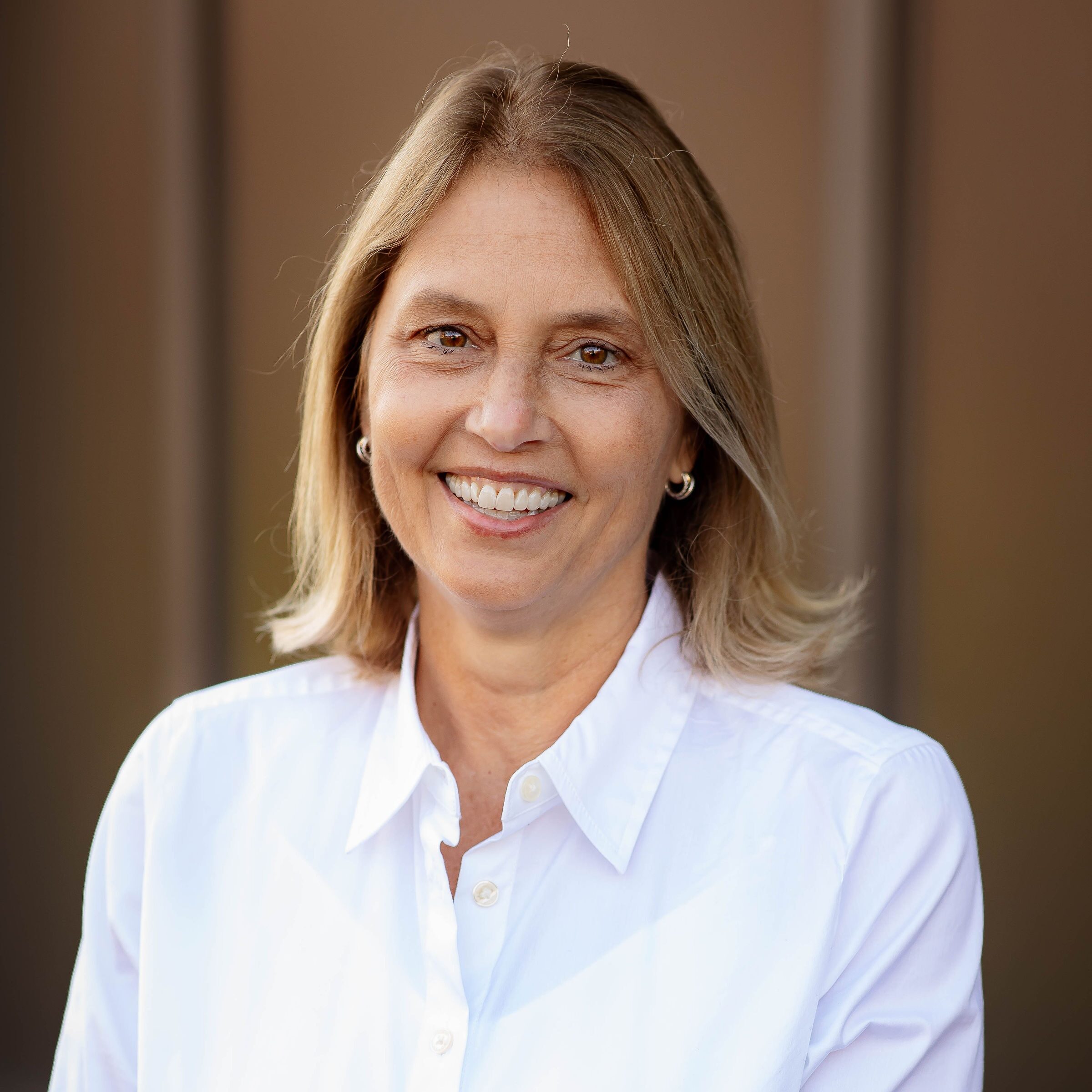Smiling person in white shirt outdoors.